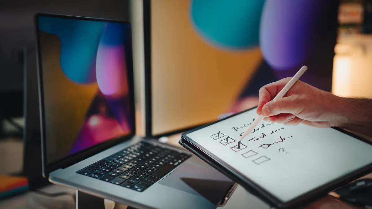 hand sketching web page wireframes beside a laptop
