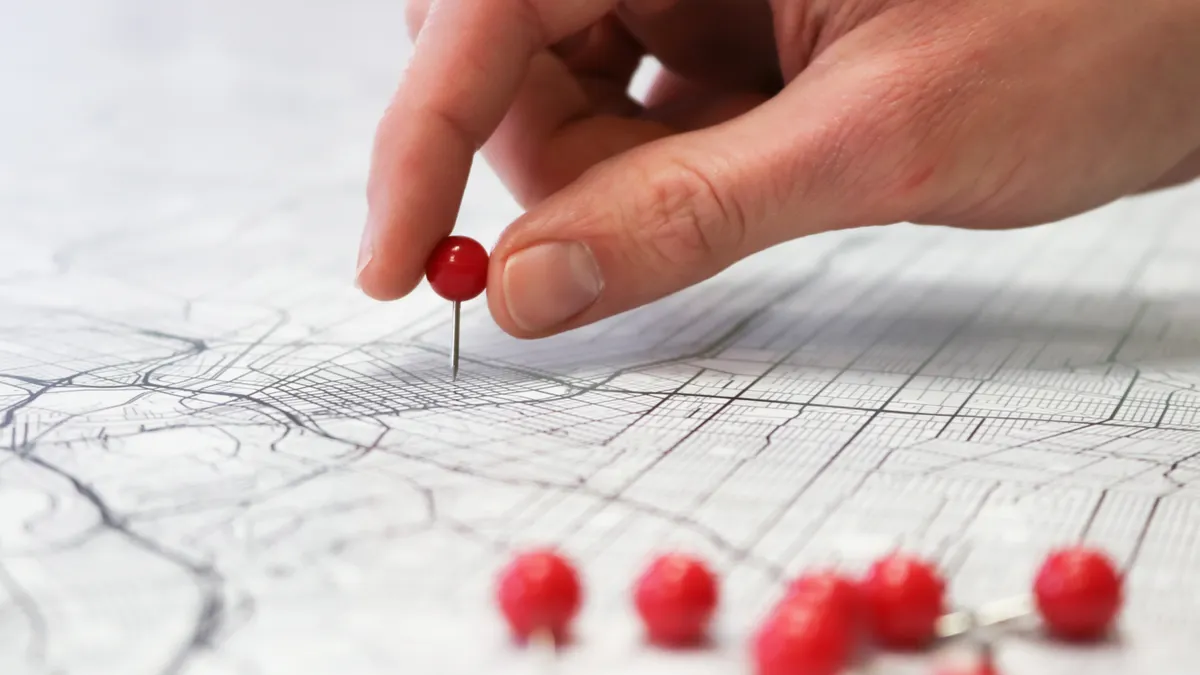 hand placing a pin on a map