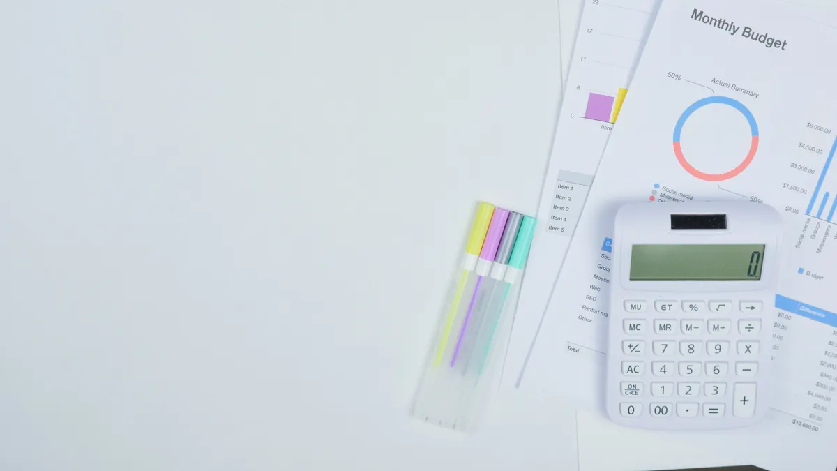 calculator beside budget charts and pens on a desk