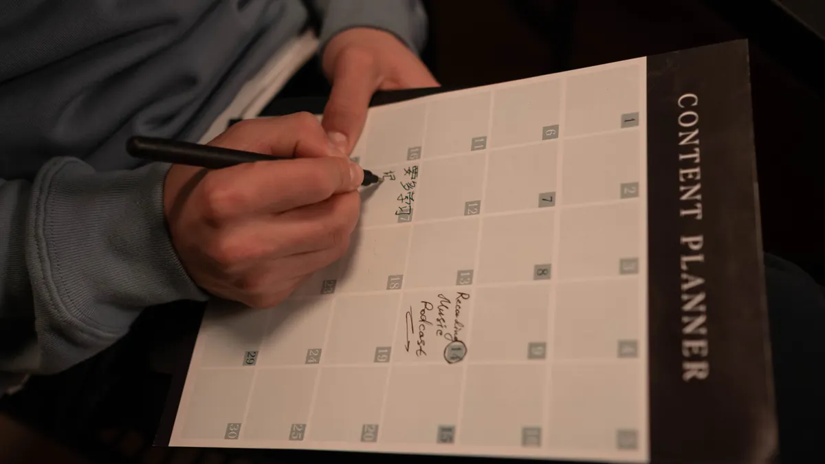 person writing in a content planner notebook
