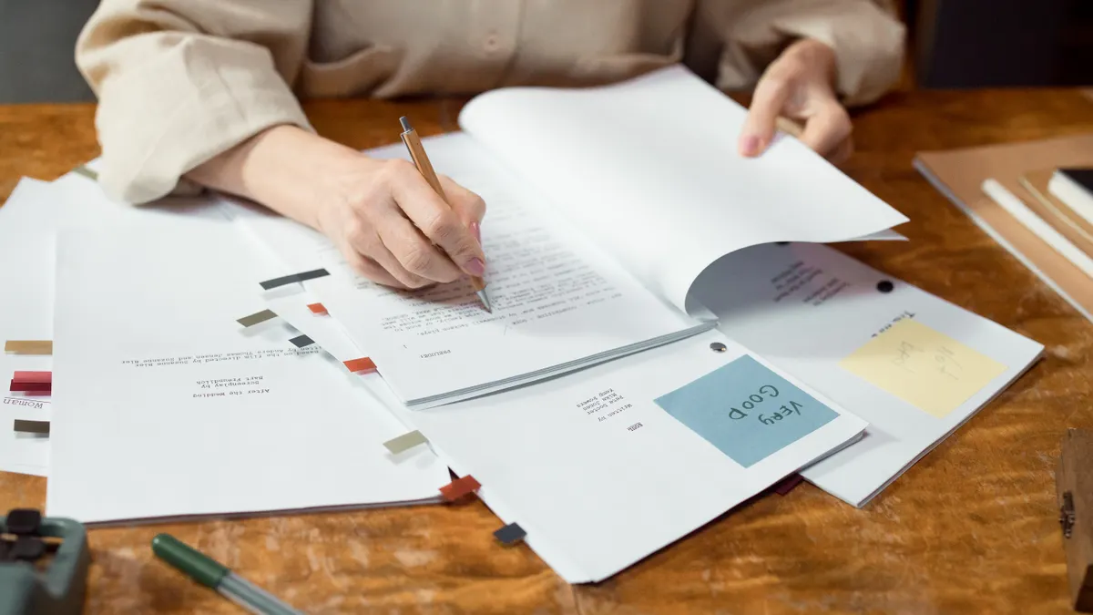 How to fix low-quality AI content before it goes live person editing a printed document with notes and page tabs