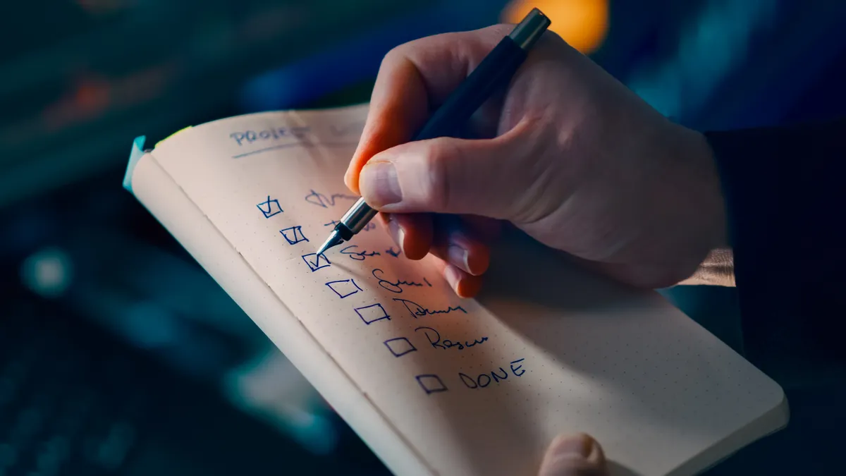 Hand ticking items on a checklist in a notebook