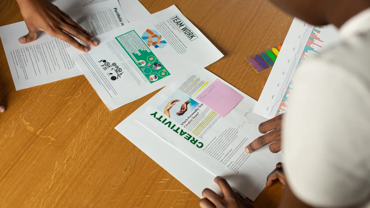two people reviewing printed design pages on a table