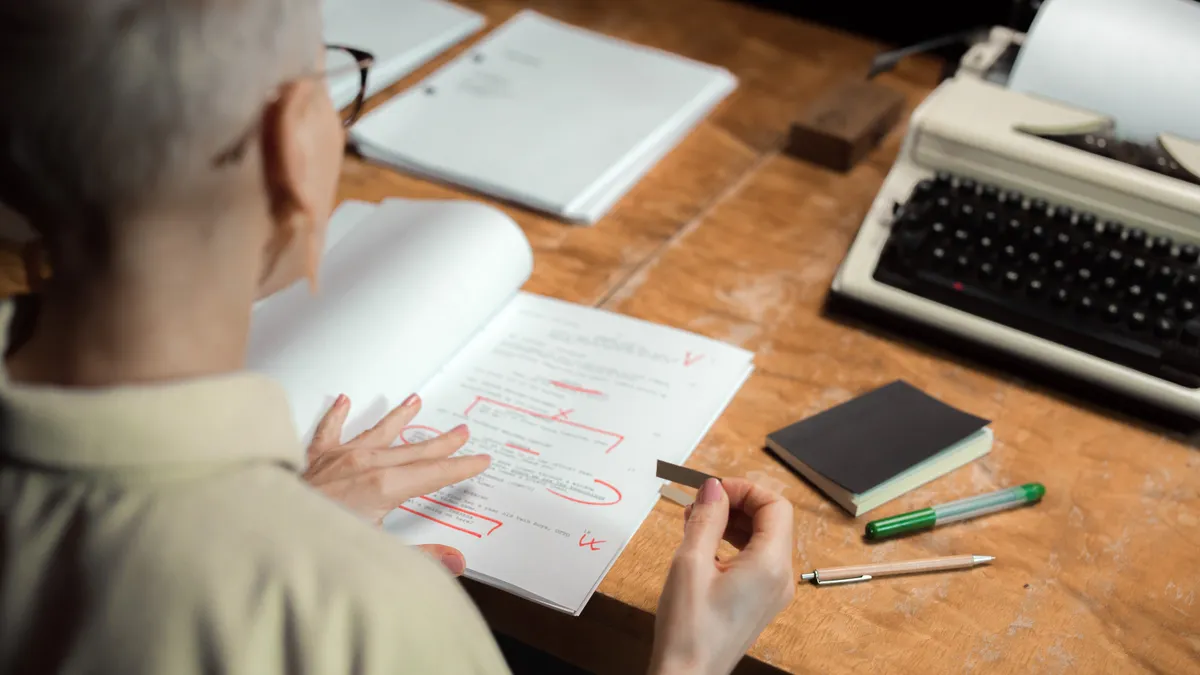 person marking up a printed document at a desk