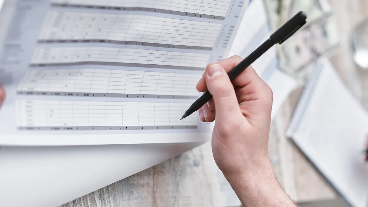 Hand reviewing a printed spreadsheet form