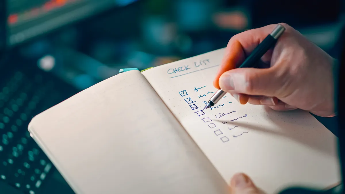 hand checking items off a checklist in a notebook